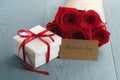 Gift box with red roses bouquet and mothers day paper card on blue wood table Royalty Free Stock Photo