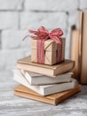 Gift Box Resting on a Stack of Various Books in an Elegant Setting With a Clean Table Corner Royalty Free Stock Photo