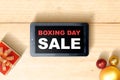 Gift box with a ribbon and Christmas ornament with Boxing Day Sale text on tablet screen Royalty Free Stock Photo