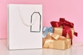 Gift box with ribbon and paper shopping bag on a pink background Royalty Free Stock Photo