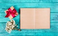 A gift box with a satin ribbon and an open book with blank pages on a blue background. Backgrounds and textures. Copy space Royalty Free Stock Photo