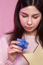 Gift box in the shape of a gold star in the hands of a young Asian girl. on a pink isolated background