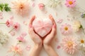 Gift box in the shape of a heart in female hands on a floral background.