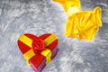 Gift box in the shape of a heart tied with a yellow ribbon with a bow in the shape of a rose lies on the pillow fake fur and next Royalty Free Stock Photo