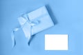 Gift box with silk ribbon in trendy blue color and empty isolated label. Flat lay. Holiday gift concept. Color of the