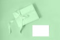 Gift box with silk ribbon in trendy neo mint color and empty isolated label. Holiday gift concept. Flat lay.