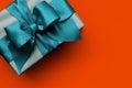 Gift box with turquoise ribbon on orange background Royalty Free Stock Photo