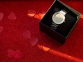 Gift box with silver watch is on red heart paper background