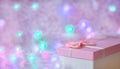 A gift box of soft pink color on a defocused background with burning lights of a garland. Festive, Christmas background. Free Royalty Free Stock Photo
