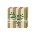 Gift box in striped wrapping with twine, string and leaf branch. Holiday present in paper package, festive surprise with Royalty Free Stock Photo