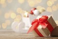 Gift box with red ribbon on table against blurred Christmas lights. Royalty Free Stock Photo