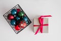 A gift box tied with a bright pink purple satin ribbon  and a metal basket with Christmas balls Royalty Free Stock Photo