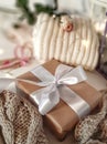 Gift box with white bowknot surrounded knitted cloths, lights, rose in soft focus.