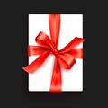Gift box. White box with a red satin bow. Bright Tape Decorates a Gift. Top View Black Background Royalty Free Stock Photo