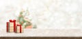 Gift box on White marble table top at blur bokeh christmas tree decor with string light background when show falling,Winter Royalty Free Stock Photo