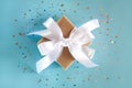 Gift box with a white ribbon and a bow on the blue background. Close-up. Top view. Banner Royalty Free Stock Photo