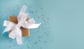 Gift box with a white ribbon and a bow on the blue background. Close-up. Top view. Copy space. Banner Royalty Free Stock Photo