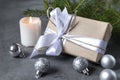 Gift box with white ribbon and rope, spruce branch, candle, silver balls on gray background, Christmas, new year Royalty Free Stock Photo