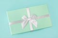 Gift box with a white silver bow, mint green on a mint turquoise background. Holiday gift minimal concept. Top view, flat lay, Royalty Free Stock Photo