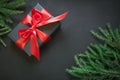Gift box wrapped in black paper with red ribbon in female hand on black surface. Top view. Christmas card. Royalty Free Stock Photo