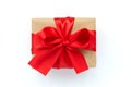 Gift box wrapped brown craft paper and red ribbon isolated on white background. Valentines day or Christmas celebration concept. Royalty Free Stock Photo