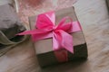 Gift box wrapped in brown craft paper and tied by pink satin ribbon. Packaging process. Gift shop. Wedding decor. Royalty Free Stock Photo