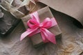 Gift box wrapped in brown craft paper and tied by pink satin ribbon. Packaging process. Gift shop. Wedding decor. Royalty Free Stock Photo