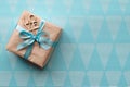 Gift box wrapped in brown paper with light blue ribbon on blue background. Freespace