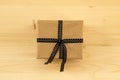 Gift box wrapped of craft paper and black ribbon on the wooden background. Royalty Free Stock Photo