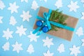 Gift box wrapped of craft paper, blue ribbon and decorated fir branches and blue Christmas balls on the blue background. Royalty Free Stock Photo