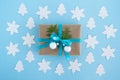 Gift box wrapped of craft paper, blue ribbon and decorated fir branches and silver Christmas balls on the blue background. Royalty Free Stock Photo