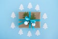 Gift box wrapped of craft paper, blue ribbon and decorated fir branches and silver Christmas balls on the blue background. Royalty Free Stock Photo
