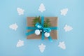 Gift box wrapped of craft paper, blue ribbon and decorated fir branches and silver Christmas balls on the blue background. Royalty Free Stock Photo