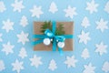 Gift box wrapped of craft paper, blue ribbon and decorated fir branches and silver Christmas balls on the blue background. Royalty Free Stock Photo