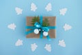 Gift box wrapped of craft paper, blue ribbon and decorated fir branches and silver Christmas balls on the blue background. Royalty Free Stock Photo