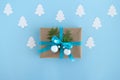 Gift box wrapped of craft paper, blue ribbon and decorated fir branches and silver Christmas balls on the blue background. Royalty Free Stock Photo