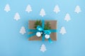 Gift box wrapped of craft paper, blue ribbon and decorated fir branches and silver Christmas balls on the blue background. Royalty Free Stock Photo