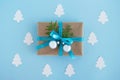 Gift box wrapped of craft paper, blue ribbon and decorated fir branches and silver Christmas balls on the blue background. Royalty Free Stock Photo