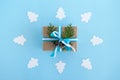 Gift box wrapped of craft paper, blue and white ribbons and decorated fir branches and pinecones on the blue background, top view.