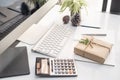 Gift box wrapped craft paper on office Desk with keyboard computer ,calculator and notebook background at home