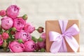 Gift box wrapped with craft paper and pink bow on pink roses background. Mother day concept Royalty Free Stock Photo