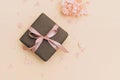 Gift box wrapped in craft paper with pink ribbon on pale orange background with hydrangea flowers Royalty Free Stock Photo