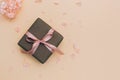 Gift box wrapped in craft paper with pink ribbon on pale orange background with hydrangea flowers Royalty Free Stock Photo