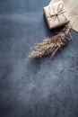 Gift box wrapped in craft paper with a reed stalk, dried pampas grass on a dark background. New fashionable home decor