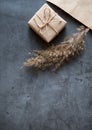 Gift box wrapped in craft paper with a reed stalk, dried pampas grass on a dark background. New fashionable home decor