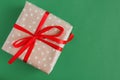 Gift box wrapped in craft polka dot paper with red ribbon on green background Royalty Free Stock Photo