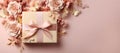 A gift box wrapped in eco-friendly craft paper with pink ribbon bow on pink background with paper flowers Royalty Free Stock Photo