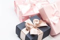 Gift box wrapped in paper with pink and gold ribbon on pink surface.