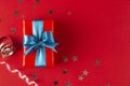 Gift box wrapped in re paper with blue ribbon on red surface. Christmas, party, birthday concept Royalty Free Stock Photo