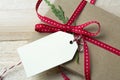 Gift box, wrapped in recycled paper, red bow and tag on wood bac Royalty Free Stock Photo